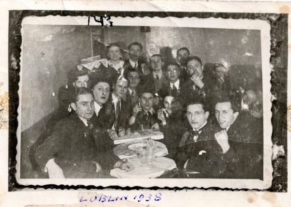 The photo shows Isaac Trachtenberg (third from left at the table) with friends; Lublin, 1938