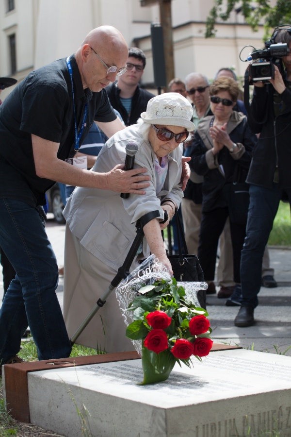 Wiesława Majczak podczas skladania kwiatów przy jednym z kubików upamiętniających drogę na Umschlagplatz