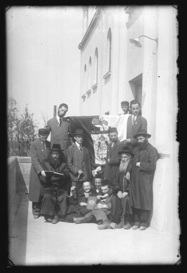 Uczniowie i kadra Jesziwy na balkonie gmachu z flagą Jesziwy.